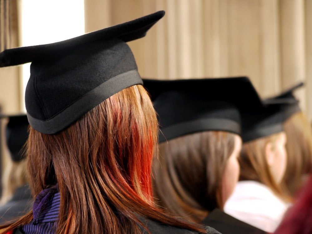 Three  university students wearing graduation gowns and hats