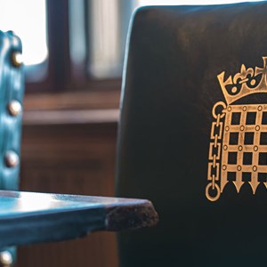 A green leather upright chair with a gold portcullis on the upright back of the chair.