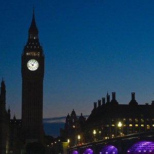 The Palace of Westminster and Portcullis House at night, with the moon in the sky.