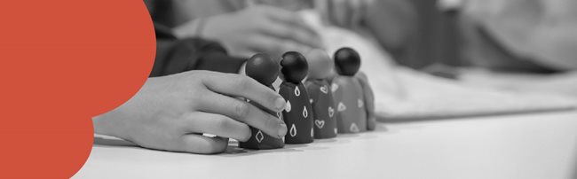 Close up of a pair of hands holding three wooden figures